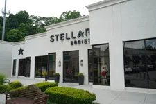 Thumbnail for Exterior view of Stellar Bodies fitness center with large windows and green landscaping in front under cloudy sky