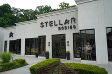 Thumbnail for Exterior view of Stellar Bodies fitness studio with modern signage and large windows surrounded by greenery