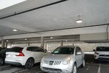 Thumbnail for Silver Nissan SUV parked in an indoor parking garage next to white and black vehicles under fluorescent lights.