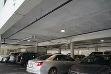 Thumbnail for Indoor parking garage with multiple parked cars under a concrete ceiling with exposed pipes and lighting.