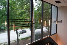 Thumbnail for Modern rectangular pendant lights hanging near large windows with a street and greenery outside.