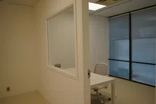 Thumbnail for Minimalist office space with a white desk, office chair, and large window with blinds.