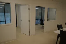 Thumbnail for Interior office space with open white doors, glass windows, black chairs, and beige flooring in a modern setting