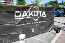 Thumbnail for Black fence banner with Dakota logo and contact info for commercial contracting at a construction site.