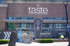 Thumbnail for Taste Wine Bar and Market storefront with construction banners and a worker in front during daytime