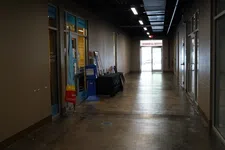 Thumbnail for Empty commercial hallway with offices, polished concrete floor, overhead lights, and glass doors leading outside.
