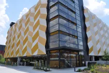 Thumbnail for Modern building with geometric yellow and white facade panels and large glass windows on a sunny day.