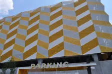 Thumbnail for Modern parking garage with geometric yellow and white patterned facade under blue sky.