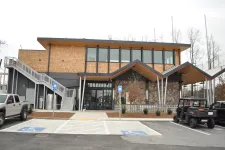 Thumbnail for Modern two-story building with wooden and stone facade, featuring large windows and handicap parking spaces in front.