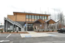 Thumbnail for Modern two-story building with angular roof, large windows, parking lot, and disabled parking spots in front.