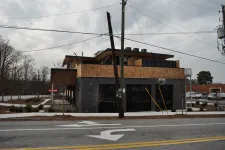 Thumbnail for Modern two-story building with wood and dark gray exterior under cloudy sky on quiet street with utility poles.