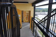 Thumbnail for Staircase leading to level 5 of a parking garage with yellow walls and large windows overlooking an industrial area.
