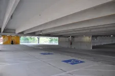 Thumbnail for Empty concrete parking garage level with visible handicapped parking spaces and structural beams overhead.