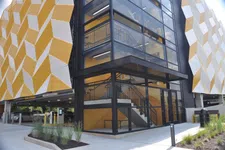 Thumbnail for Modern parking garage exterior with geometric yellow and white panels and glass-enclosed stairwell.