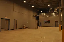 Thumbnail for Spacious empty industrial warehouse with smooth concrete floor, gray walls, high ceiling, and overhead lights.