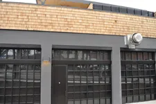 Thumbnail for Modern commercial building facade with large grid windows, dark door, gray stucco, and wooden shingle trim.