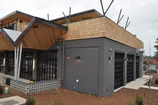 Thumbnail for Modern commercial building with gray brick walls, wooden accents, large windows, and geometric roof design