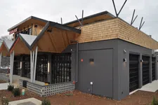 Thumbnail for Modern restaurant building with black brick walls, large windows, and wooden shingle roofing under gray sky
