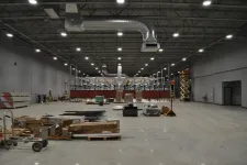 Thumbnail for Interior of a large industrial warehouse under construction with materials and equipment scattered on polished concrete floor.