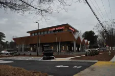 Thumbnail for Modern two-story Killer Burgers restaurant with stone facade, angular roof, parked truck, and overcast sky.