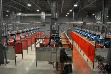 Thumbnail for Industrial welding facility with multiple workstations separated by red curtains and ventilation systems overhead.