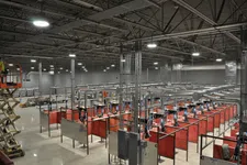 Thumbnail for Industrial workshop with red welding booths and extensive ductwork under high ceiling lights in a spacious warehouse.