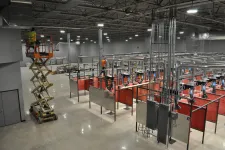 Thumbnail for Worker on scissor lift in a large industrial welding training facility with ventilation and red partitions.