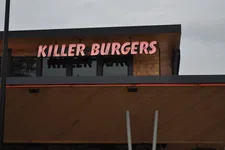 Thumbnail for Killer Burgers neon sign on a modern wooden and glass restaurant facade during overcast weather.