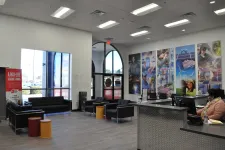 Thumbnail for Modern office lobby with black sofas, colorful stools, large windows, and vibrant work-themed wall art.
