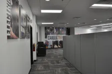Thumbnail for Office hallway with gray cubicles and career conference banner at the end of the corridor.