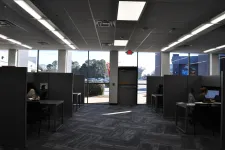 Thumbnail for Modern office space with cubicles, desks, computers, and large windows showing outdoor parking lot.