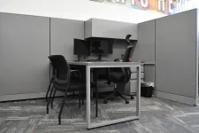 Thumbnail for Modern office cubicle with gray walls, two black chairs, dual monitors, and a desk with gray metal frame.