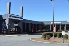 Thumbnail for Exterior view of Tulsa Welding School building with signage, flags, and clear blue sky at 1287 address.