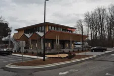 Thumbnail for Modern Killer Burgers restaurant building with angled roof, stone exterior, and parking lot under cloudy sky