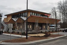 Thumbnail for Modern Killer Burger restaurant with sharp angled roof, large windows, and parking lot on a cloudy day
