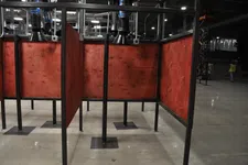 Thumbnail for Empty industrial workstations with red wooden panels and black metal frames in a large factory space.