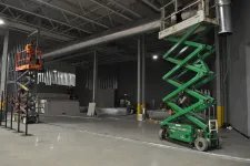 Thumbnail for Workers using scissor lifts inside a large industrial warehouse under construction with metal framing and concrete floors