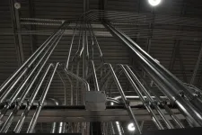 Thumbnail for Multiple metal electrical conduits mounted on ceiling beams in an industrial setting.