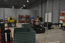 Thumbnail for Industrial warehouse interior with metal machinery, stacked materials, and equipment on concrete floor under high ceiling.