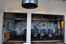 Thumbnail for Modern conference room with patterned wall art, black chairs, pendant lights, and a mounted flat screen TV.