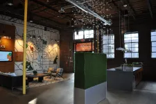 Thumbnail for Modern industrial-style office with exposed brick, seating area, large map mural, and decorative hanging elements.