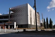 Thumbnail for Modern parking garage with geometric facade, trees, and blue sky in an urban setting on a sunny day