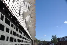 Thumbnail for Modern building facade with geometric patterns and protruding white triangular shapes under a clear blue sky.