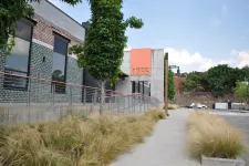 Thumbnail for Modern commercial building with large windows, tall grass landscaping, and number 1755 on orange panel.