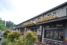 Thumbnail for Exterior view of a brick food market with illuminated Food Works sign and greenery in front on a clear day