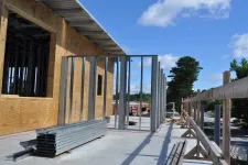 Thumbnail for Commercial building under construction with metal framing and plywood sheathing on a clear sunny day.