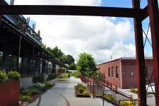 Thumbnail for Outdoor walkway between modern commercial buildings with greenery, flowers, and partly cloudy sky overhead