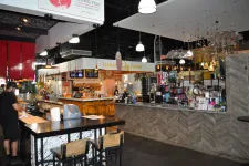 Thumbnail for Modern food court interior with sushi bar, colorful decor, hanging lamps, and seating areas with customers.