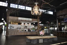 Thumbnail for Modern cafe interior featuring a wooden bench table, chandelier, and UnbeliBubble counter under tall windows.