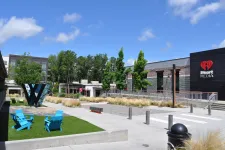Thumbnail for Outdoor seating area with blue chairs, a large 'W' sculpture, greenery, and iHeart Media building under a clear blue sky